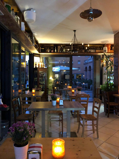 Sala interna del Caffè Martini Bistrot a Cesena con tavoli in legno, luci calde e vetrate affacciate sul centro storico